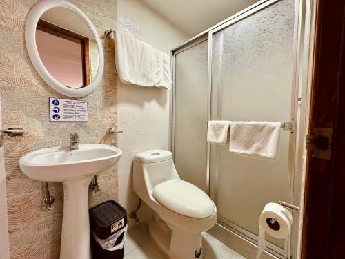 a bathroom with a sink and a toilet and a mirror at Hotel Tiwintza Internacional in Quito
