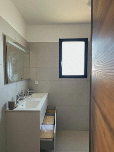 une salle de bain avec un lavabo et une fenêtre dans l'établissement Bel Appartement Vieux Port Porto-Vecchio, à Porto-Vecchio