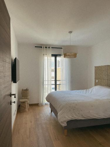 une chambre avec un lit et une grande fenêtre dans l'établissement Bel Appartement Vieux Port Porto-Vecchio, à Porto-Vecchio