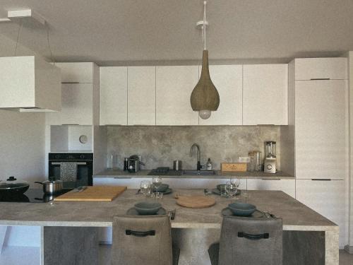 une cuisine avec des armoires blanches et un îlot avec des tabourets dans l'établissement Bel Appartement Vieux Port Porto-Vecchio, à Porto-Vecchio