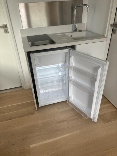 - un réfrigérateur vide dans une cuisine avec évier dans l'établissement Studio suite climatisé avec balcon, kitchenette équipée, douche, baignoire, wc et bureau, à Genay