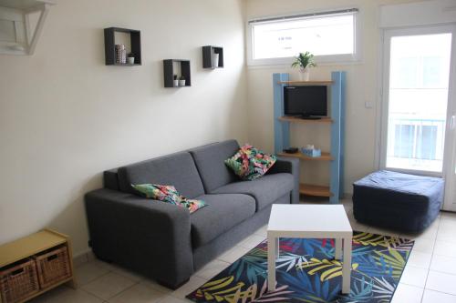 un salon avec un canapé et une télévision dans l'établissement Charmant studio en bord de mer, à Pornichet