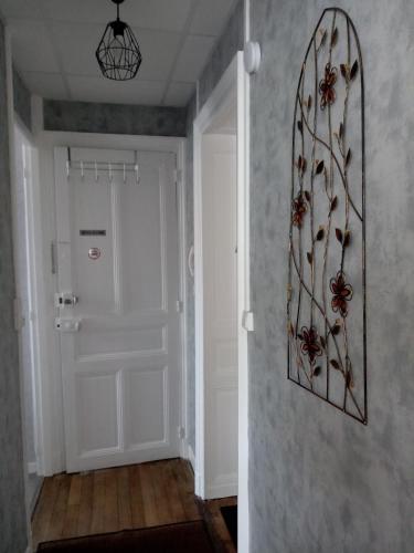 un couloir avec une porte blanche avec une image de fleur sur le mur dans l'établissement Appartement Les fleurs du parc classé 3 étoiles, à Vittel