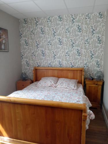 - une chambre avec un lit en bois et du papier peint floral dans l'établissement Appartement Les fleurs du parc classé 3 étoiles, à Vittel