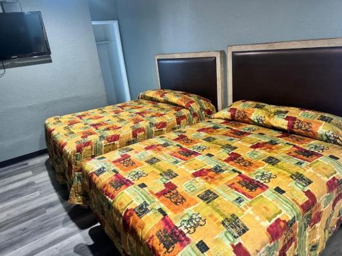 a bedroom with two beds with a colorful quilt at King Castle Motel in Los Angeles