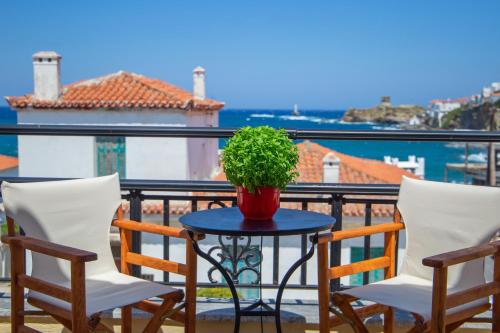 a table with chairs and a potted plant on a balcony at Seaview comfy flat in Andros - walk to beach in Andros