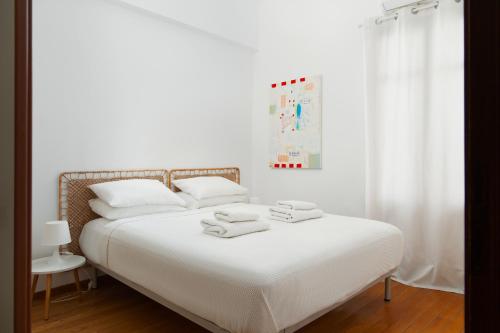 a white bedroom with a bed with towels on it at Seaview comfy flat in Andros - walk to beach in Andros