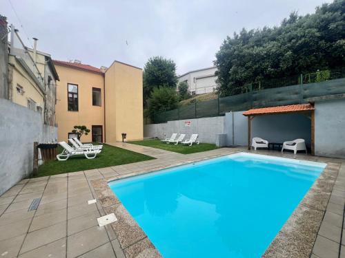a large blue swimming pool in a yard with chairs at OPORTO WINE LOFTS in Vila Nova de Gaia
