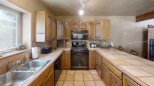 a kitchen with wooden cabinets and a stove and a sink at River Ritz - Pet Friendly - WiFi - Near the Ski Area - Fireplace - On the River - Washer - Dryer - in Red River