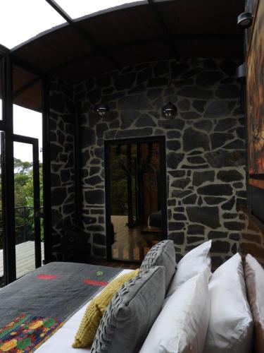 a room with a stone wall with a bed and a mirror at La Gloria Reserva Forestal in La Calera