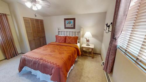a bedroom with a bed with an orange bedspread at River Ritz - Pet Friendly - WiFi - Near the Ski Area - Fireplace - On the River - Washer - Dryer - in Red River