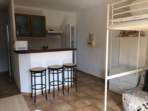 une cuisine avec trois tabourets de bar dans une chambre avec un lit superposé dans l'établissement Studio avec balcon - Plage à 10min à pied, au Pradet