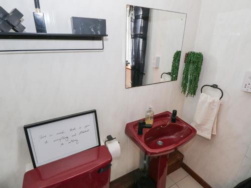 Un baño con un lavabo rojo y un espejo. en Ben Gower, en Glentrasna