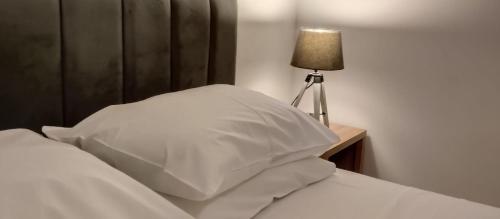 un letto con cuscini bianchi e un tavolo con una lampada di Beach Side Apartment a Vlorë