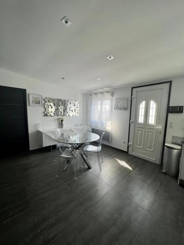 une salle à manger avec une table en verre et une cuisine dans l'établissement La Maisonnette Palavasienne, à Palavas-les-Flots