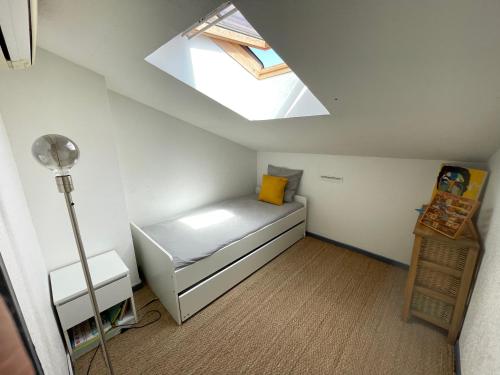 Cette petite chambre comprend un lit et une lucarne. dans l'établissement Cocon douillet avec jardin près de la mer, à Carqueiranne