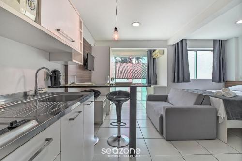 a kitchen with a sink and a couch in a room at SPT - Studios Convenientes em Blumenau/SC in Blumenau