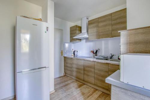 La cuisine est équipée d'un réfrigérateur blanc et de placards en bois. dans l'établissement T3 avec garage - proche Port & Plage, à Toulon