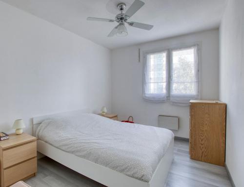 une chambre blanche avec un lit et un ventilateur de plafond dans l'établissement T3 avec garage - proche Port & Plage, à Toulon