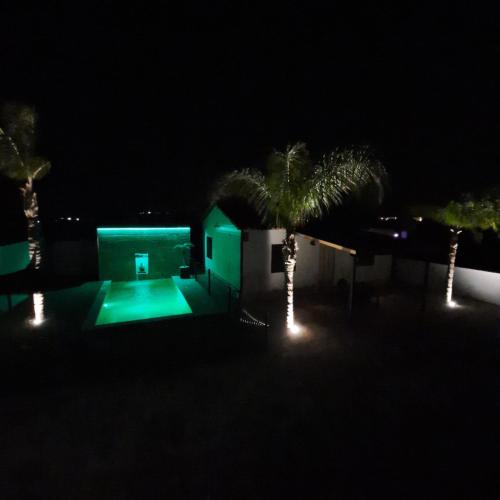 a green house with palm trees and lights at night at Chalet con encanto en Conil SOLO FAMILIAS Y PAREJAS in Conil de la Frontera