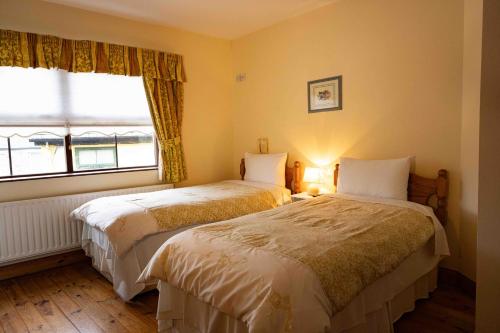 two beds in a room with a window at McCarthy's Westport in Westport