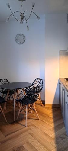 a table and chairs in a kitchen with a clock on the wall at Spacerowa, centrum, 2 pokoje, balkon, dla 1- 4 osób in Piła