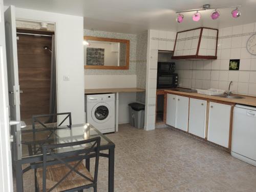 une cuisine avec une table et une machine à laver dans l'établissement Grand 2 pièces atypique aux portes de la Vallée de Chevreuse, à Châteaufort