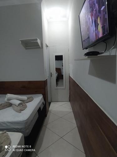 a small room with two beds and a flat screen tv at Pousada Quarto Privativo a 600 mts da basílica nova in Aparecida