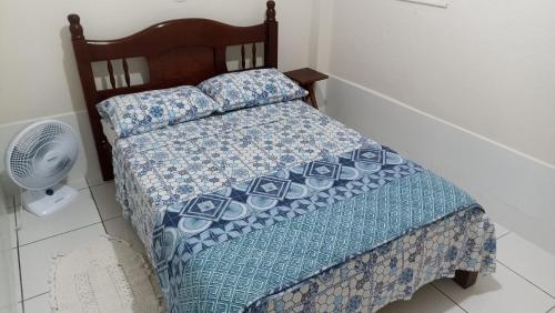 a bedroom with a bed with a blue quilt and a fan at Estalagem Alejandro in Cunha