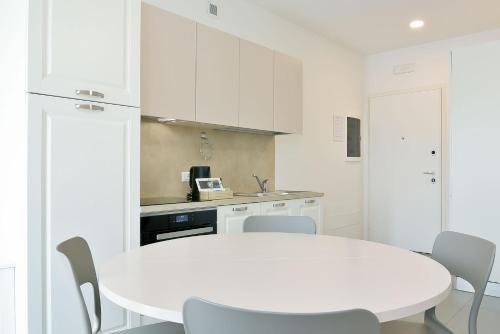 a white kitchen with a white table and chairs at Queen Venice Fly Apartments in Campalto