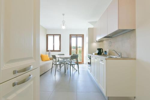 a kitchen with white cabinets and a table with chairs at Queen Venice Fly Apartments in Campalto