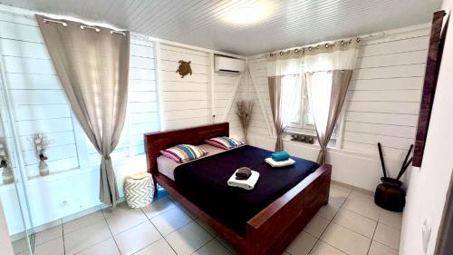 a small bedroom with a bed and a tub at MAJO LOUNGE dans un jardin tropical à 5 min de la mer Caraïbe in Saint-Pierre