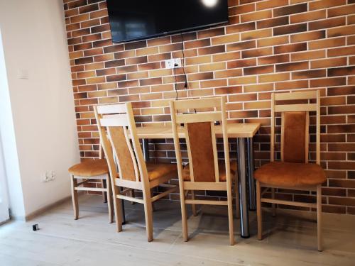 a table and four chairs against a brick wall at Extra Apartament Leśny Miodek Sielpia Wielka in Sielpia Wielka