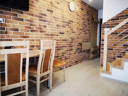 a brick wall in a room with a table and chairs at Extra Apartament Leśny Miodek Sielpia Wielka in Sielpia Wielka