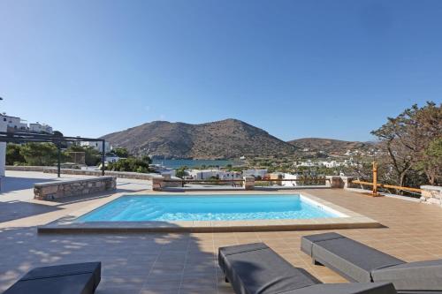 a pool with chairs and a view of the water at Caldera Suites "Φάρος" in Galissas