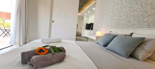 a bedroom with a white bed with an orange on it at Papaya Apartments Sal Island in Santa Maria