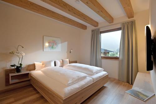 a bedroom with a large white bed with a window at Resort Tirol Brixen am Sonnenplateau in Brixen im Thale