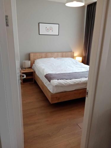 a bedroom with a bed with white sheets and wooden floors at HOTEL ARCHI KOKHTA BAKURIANI in Bakuriani