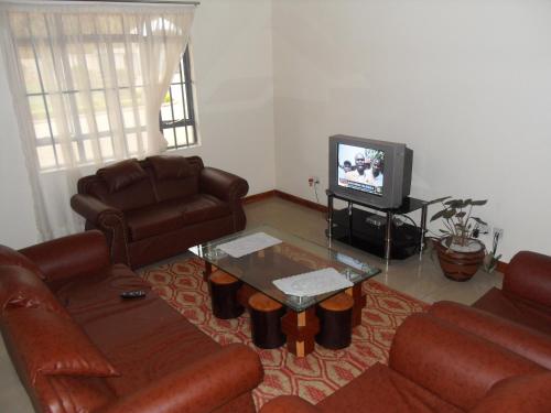 a living room with leather furniture and a tv at Mirema Hotel in Nairobi