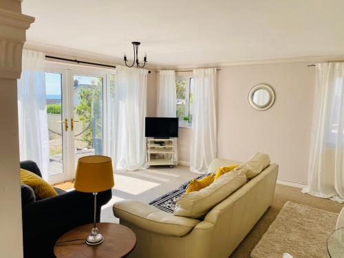 a living room with a couch and a tv at Stylish apartment - 2 min walk from Ogmore by sea beach with private garden, sea views & stunning sunsets, dog friendly in Tythegston