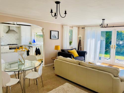 a living room with a couch and a glass table at Stylish apartment - 2 min walk from Ogmore by sea beach with private garden, sea views & stunning sunsets, dog friendly in Tythegston