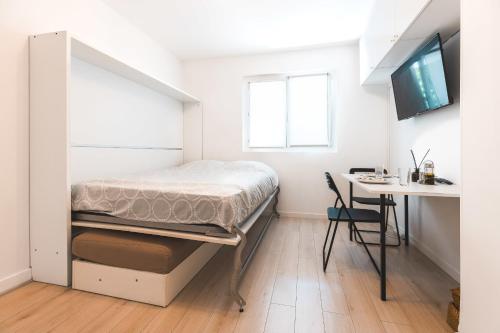 une petite chambre avec un lit et un bureau dans l'établissement Le Tresum - Studio near Annecy Lake, à Annecy