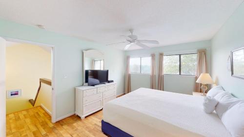 a white bedroom with a bed and a television at Heron Marsh Escape Split Level Villa Lake Views in Pawleys Island