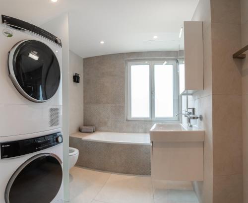 a bathroom with a tub and a sink and a washing machine at Ästhetische Wohnung, zentral gelegen! in Winterthur
