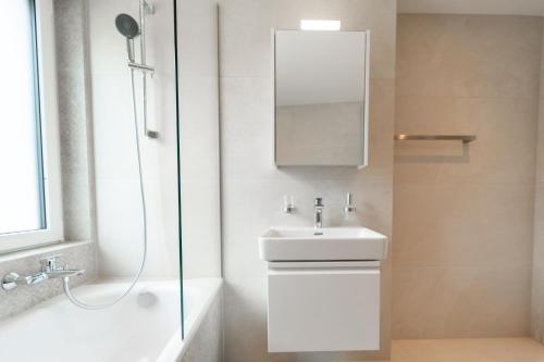 a white bathroom with a sink and a shower at Ästhetische Wohnung, zentral gelegen! in Winterthur