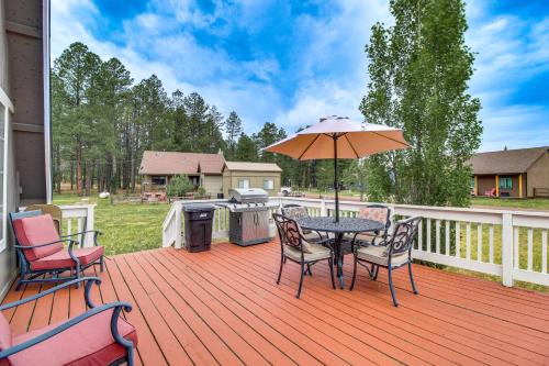 a patio with a table and chairs and an umbrella at Mountain-View Cabin in Pinetop with Fire Pit and Yard in Pinetop-Lakeside
