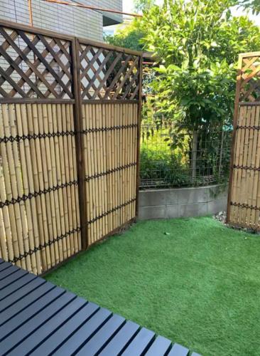a wooden fence with green grass in a backyard at Small House Near Narita Airport in Shisui
