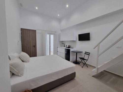 a white bedroom with a bed and a kitchen at Majo Suites Hotel in Agia Anna Naxos