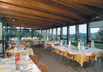 a restaurant with white tables and chairs and windows at Hotel Kristall in Monghidoro