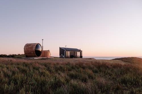 a house on the edge of a field next to the ocean at Red Rock Hut, King Island in Yambacoona